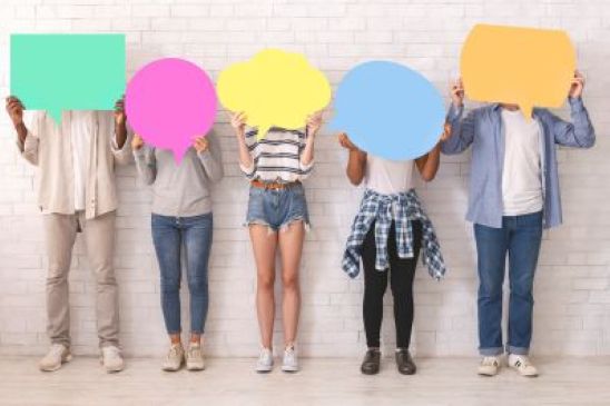 Five young people in a line holding colourful cardboard speech bubbles